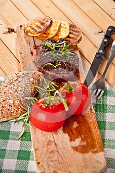 Grilled beef steak, baked potatoes and vegetable on wooden bread