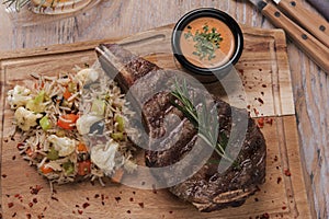Grilled beef steak on bone striploin with rice and vegetables