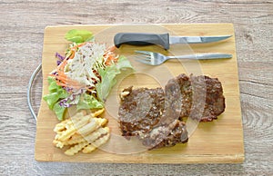 Grilled beef steak dressing barbecue sauce  with French fries and salad on chopping block