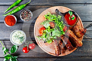 Grilled Beef steak with fresh vegetable salad, tomatoes and sauce on wooden cutting board.