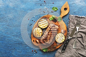 Grilled beef steak, herbs and spices on a blue rustic background. Top view, flat lay.