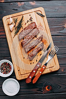 Grilled beef steak with herbs and spices on cutting board and cu