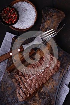 Grilled beef steak with knife and fork on cutting board