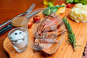 Grilled beef steak with mashed potatoes and vegetables on a wooden board with spices