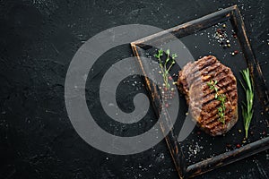 Grilled beef steak medium rare on a black stone table. Top view.