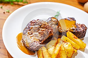 Grilled beef steak with potato wedges on white plate
