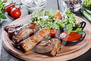 Grilled Beef steak Ribeye with fresh vegetable salad, tomatoes and sauce on wooden cutting board.