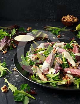 Grilled Beef Steak salad with pears, walnuts and greens vegetables and blue cheese sauce. healthy food.