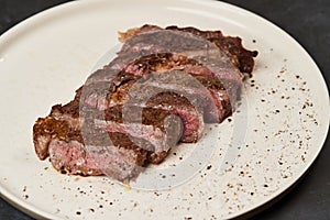 Grilled beef steak with spices on a white tray, close-up