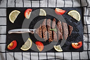 Grilled beef steak, Tenderloin on black stone plate with Rosemary, tomato and lemon