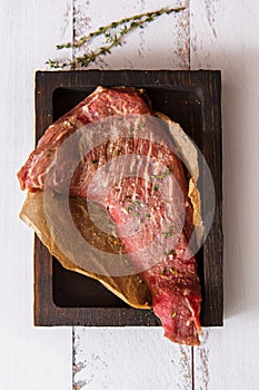 Grilled beef steak with thyme, salt and pepper on cutting board