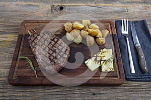 Grilled beef steak with tomatoes, garlic with chimichurri sauce on meat cutting board