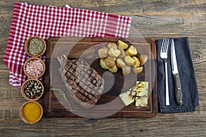 Grilled beef steak with tomatoes, garlic with chimichurri sauce on meat cutting board