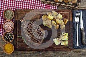 Grilled beef steak with tomatoes, garlic with chimichurri sauce on meat cutting board