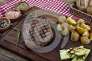 Grilled beef steak with tomatoes, garlic with chimichurri sauce on meat cutting board