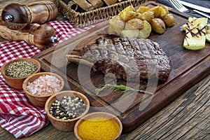 Grilled beef steak with tomatoes, garlic with chimichurri sauce on meat cutting board