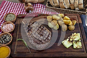 Grilled beef steak with tomatoes, garlic with chimichurri sauce on meat cutting board