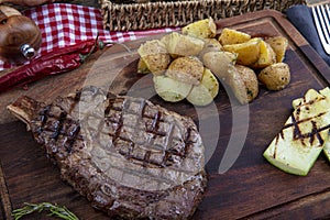 Grilled beef steak with tomatoes, garlic with chimichurri sauce on meat cutting board