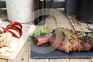 Grilled beef steak on wooden table top. Healthy food concept. Beef cut outdoors, garden kitchen, bbq grill patio