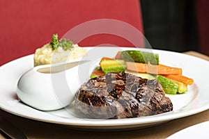 Grilled beef steaks with spices with vegetables, mashed potato, and mushroom sauce