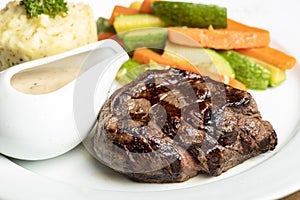 Grilled beef steaks with spices with vegetables, mashed potato, and mushroom sauce