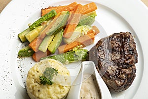 Grilled beef steaks with spices with vegetables, mashed potato, and mushroom sauce