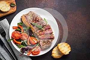 Grilled beef striploin steak with fresh salad top view.