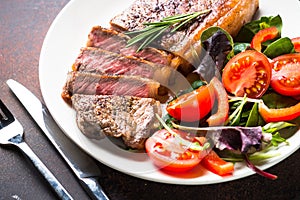 Grilled beef striploin steak with salad in plate.