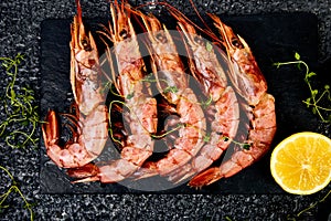 Grilled big tiger shrimps prawns on black slate plate photo