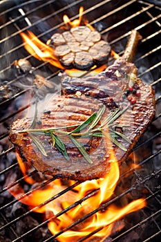 Grilled bone-in pork chop, pork steak, tomahawk in a rosemary-garlic marinade  on a flaming grill