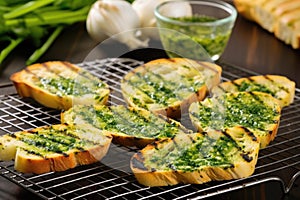 grilled bread on a cooling rack, dollop of garlic herb butter on side