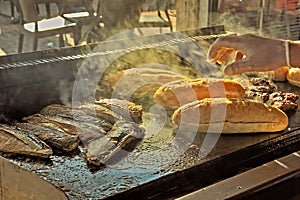 grilled bread and fish, the cook prepares hot turkish balik ekmek / fish sandwich, flashing, smoke