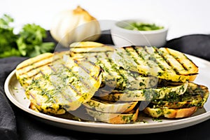 grilled bread slices served on a plate, basted with garlic herb butter