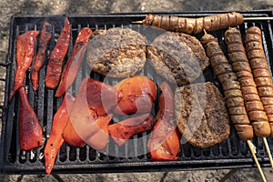 Grilled Burgers, Hot Dog Sausage and Red Peppers on a Barbecue Grill