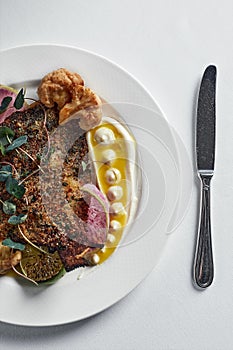 Grilled cabbala fish. on a light background, banquet serving of a dish of flounder with sheep and cauliflower top view