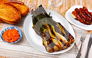 Grilled calcots served with romesco sauce, botifarra and toasts