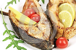 Grilled carp steaks with lemon and tomatoes.