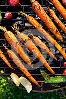 Grilled carrots in a herbal marinade on a grill plate, outdoor, top view.