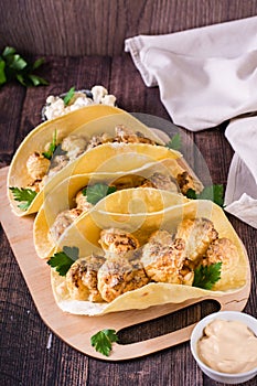 Grilled cauliflower tacos with herbs on a board on the table. Vegetarian food. Vertical view