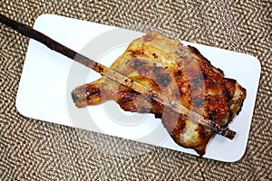 grilled chicken with bamboo sticks on mat