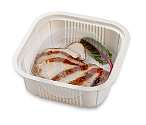 Grilled chicken breast cut into slices. In a plastic container. Food to go. On a light background