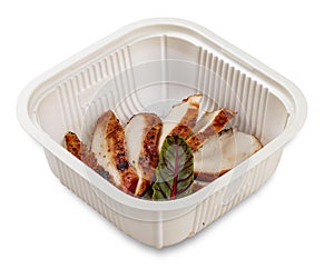 Grilled chicken breast cut into slices. In a plastic container. Food to go. On a light background