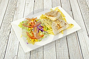 Grilled chicken breast fillets with french fries and salad of lettuce, sweet corn and tomato, carrot