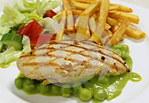 Grilled chicken breast on pea puree side view