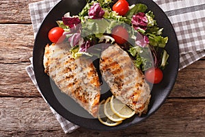 Grilled chicken breast with salad of chicory, tomatoes and lettuce close-up. horizontal top view
