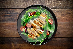 Grilled chicken breast and salad. Fresh vegetable salad with tomato, arugula, spinach and grilled chicken meat in bowl