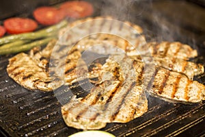 Grilled chicken breast with sausage, fries and salad on grill