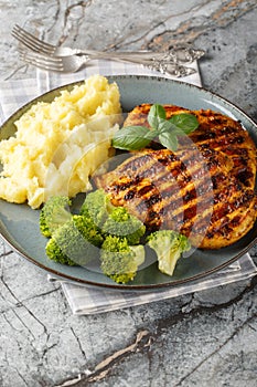 Grilled chicken breast served with mashed potatoes and broccoli close-up in a plate. Vertical