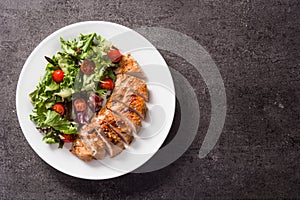 Grilled chicken breast with vegetables on a plate on black background