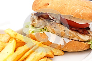 Grilled chicken burger with chips on white plate.